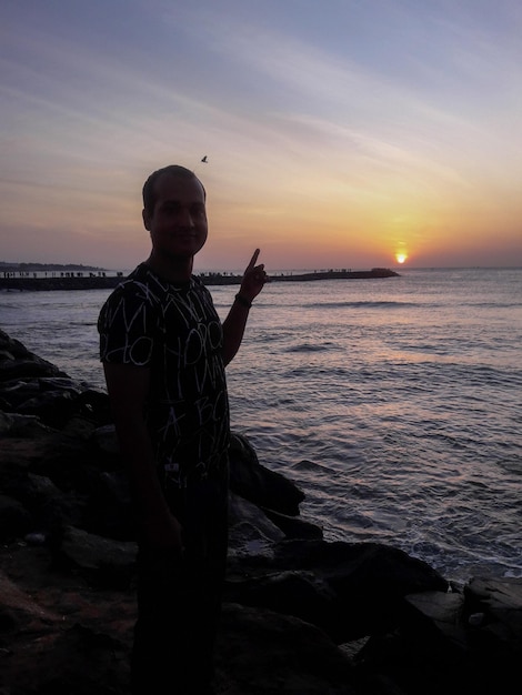 Foto uomo in piedi sulla spiaggia contro il cielo durante il tramonto