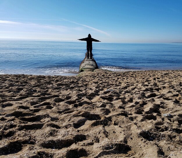 Uomo in piedi sulla spiaggia contro il cielo