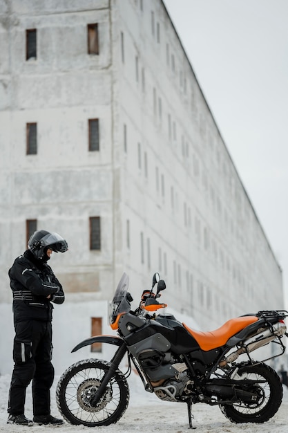 Foto uomo in piedi accanto a moto con casco