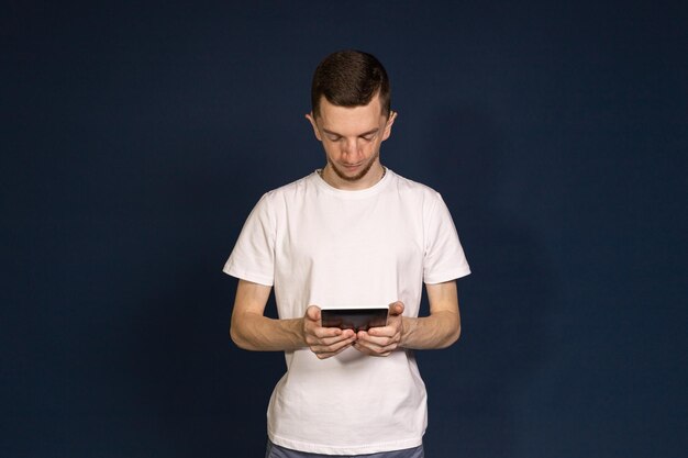 A man standing on a blue background holding a tablet