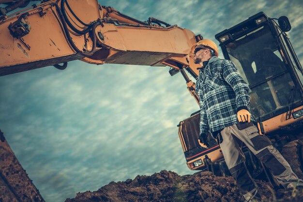 Photo man standing by earth mover against sky