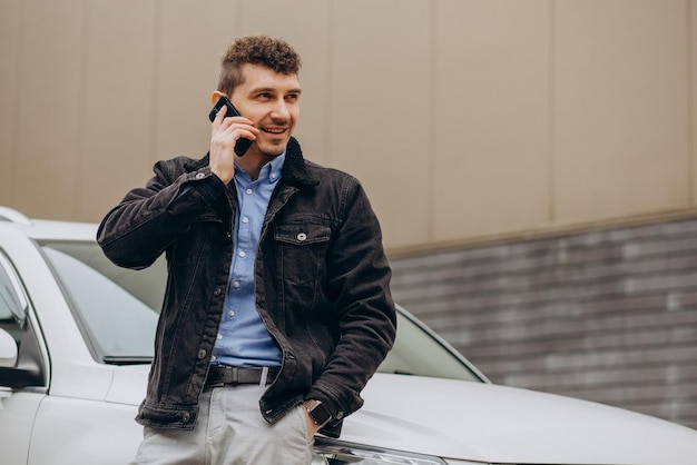 Man standing by his car and talking on the phone