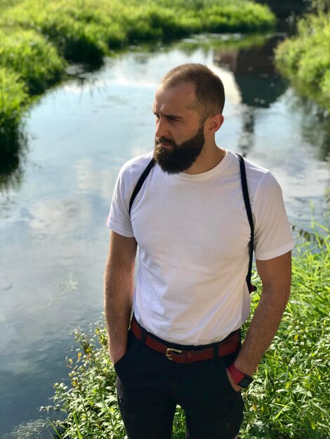 Foto uomo in piedi vicino al lago contro la pianta