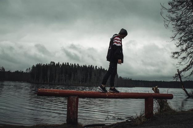 写真 冬の空に向かって湖のそばに立っている男