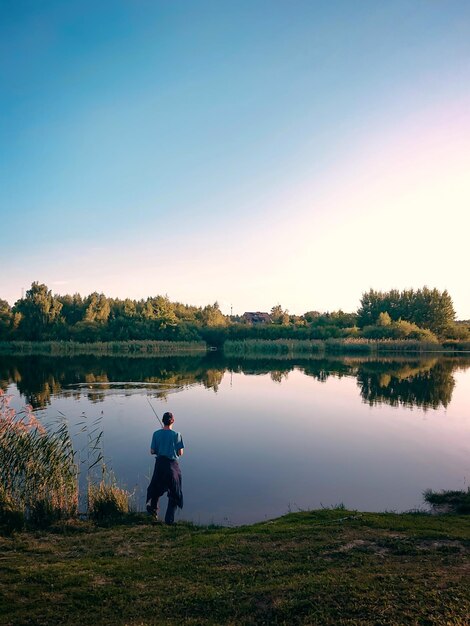 Photo man standing by lake against sky