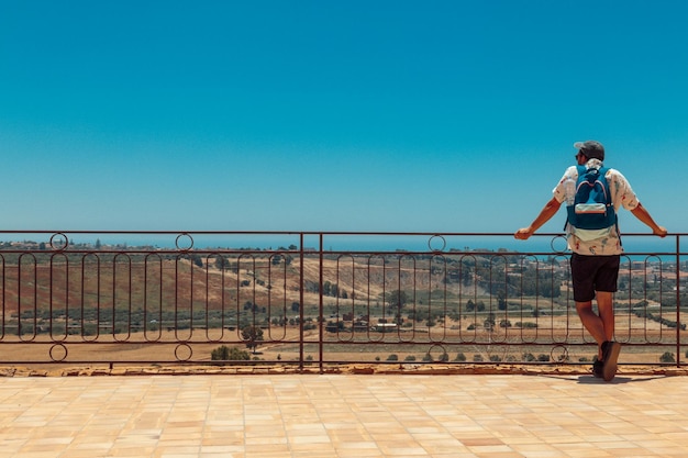 Foto uomo in piedi vicino alla ringhiera contro il cielo blu limpido