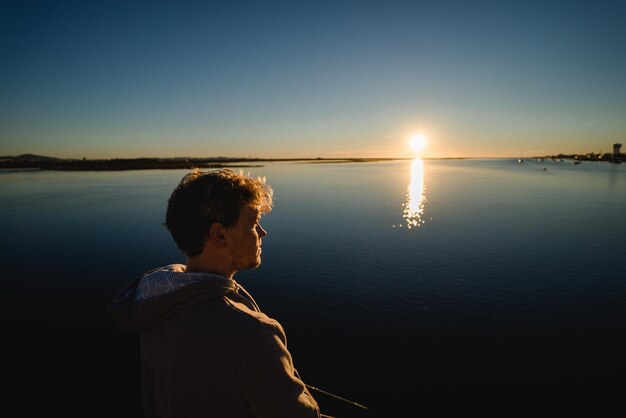 写真 晴れた空に沿って海に立っている男