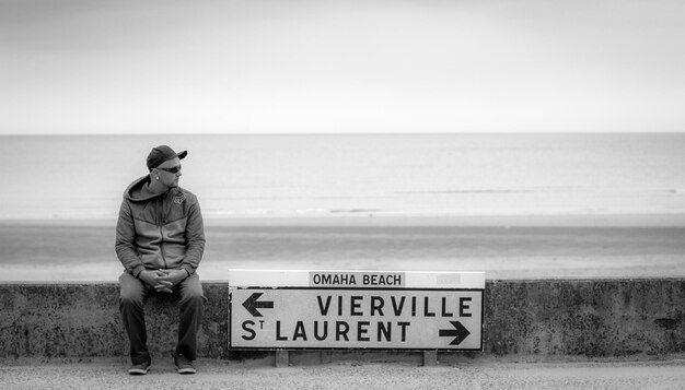 写真 晴れた空の下のビーチでテキストで立っている男