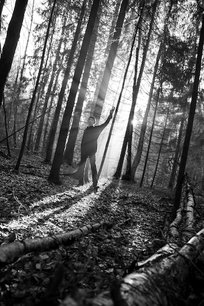 Foto uomo in piedi accanto agli alberi nella foresta