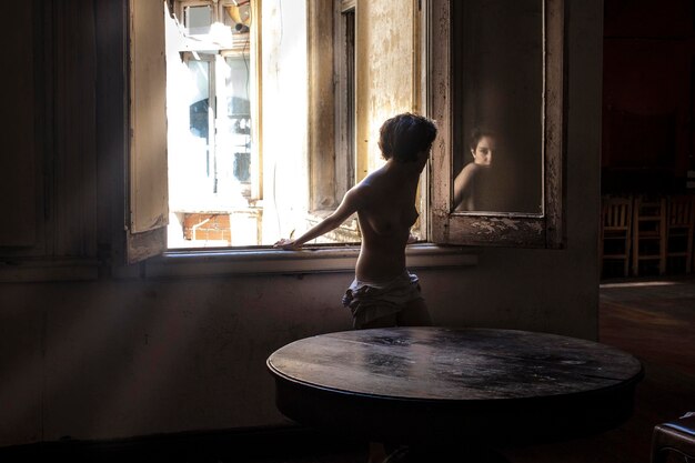 Foto uomo in piedi vicino alla finestra a casa