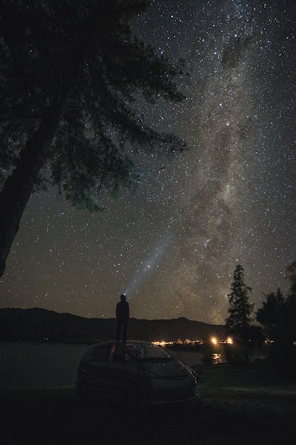 Man standing on car looking at milky way galaxy