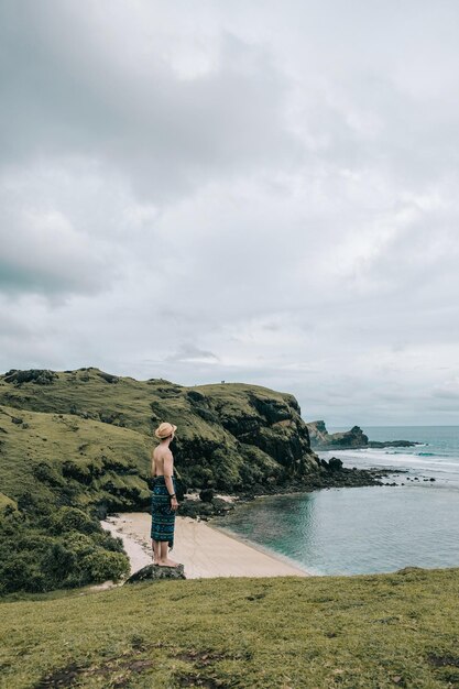 Man standing on cliff at beach against sky