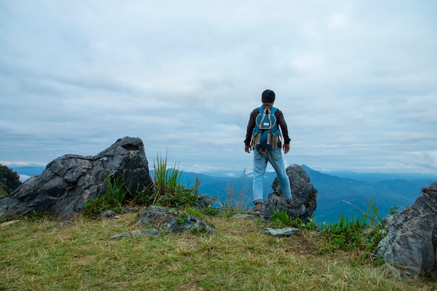 崖の上に立っていると日光の下で谷や山々を見ている男