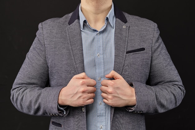 A man standing confidently holding a jacket on a black background.