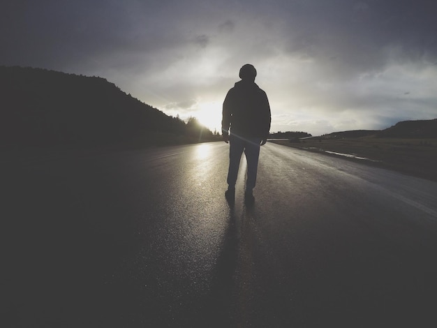 Foto uomo in piedi su una strada di campagna contro il cielo