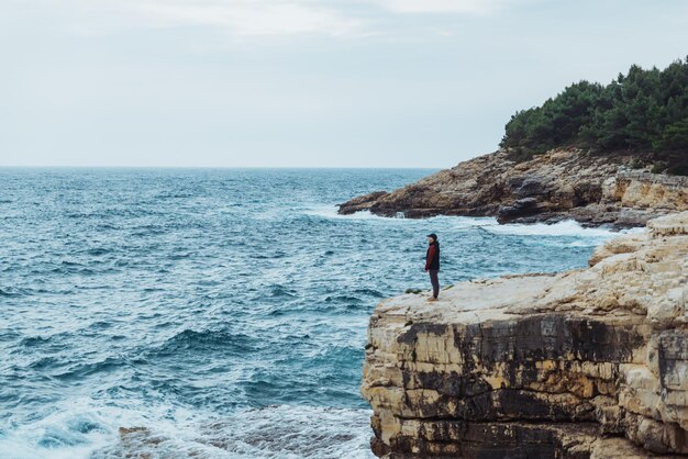 海の風の強い天気を見ている端に立っている男