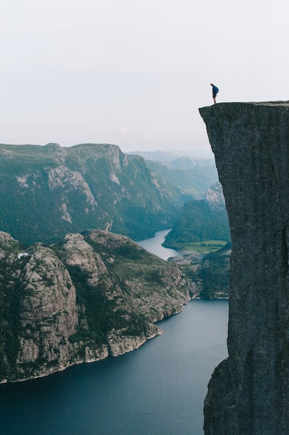 Foto uomo in piedi sul bordo di preikestolen, norvegia