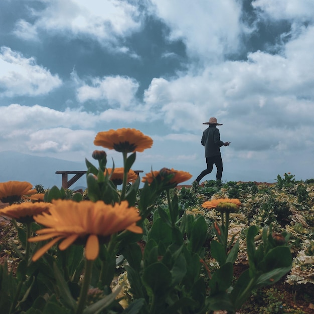 Foto uomo in piedi sul campo contro un cielo nuvoloso