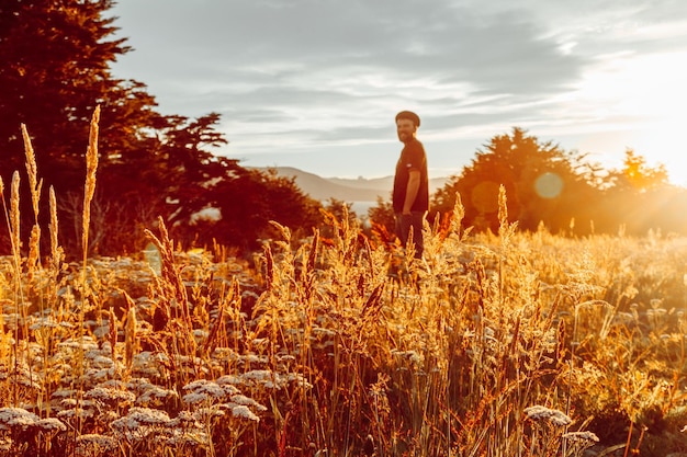 man standing on field against sky at sunset