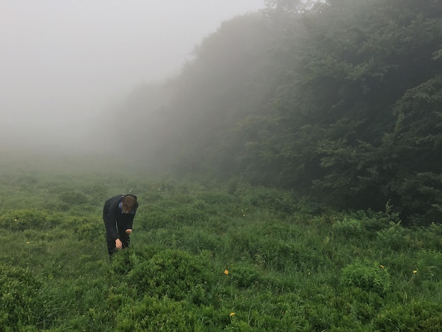 Photo man standing on field during foggy weather