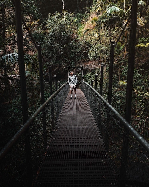 Photo man standing on footbridge in forest