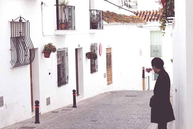 Photo man standing on footpath amidst buildings