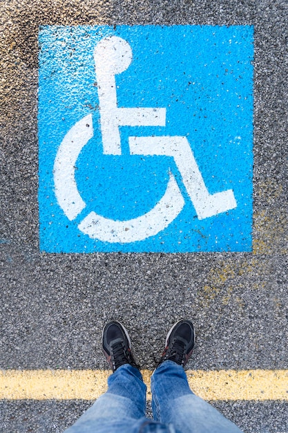 Foto un uomo in piedi di fronte al simbolo sui ciottoli nell'area per persone disabili