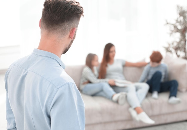 Man standing in his living room and looking at his family