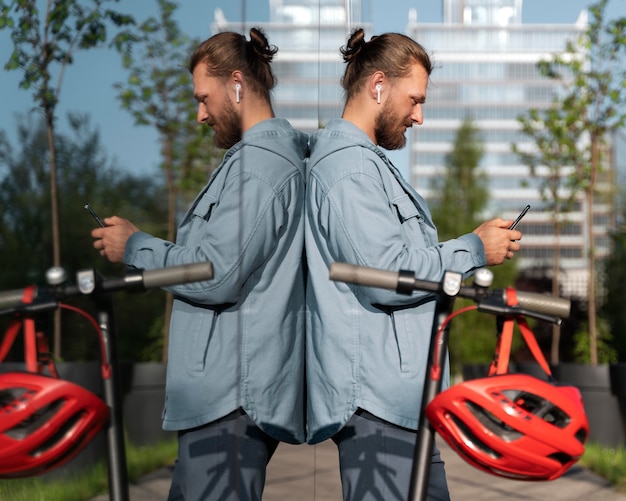 Foto uomo in piedi accanto al suo scooter mentre controlla il suo telefono