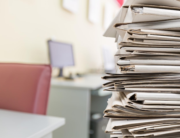 man standing next to huge stack of files