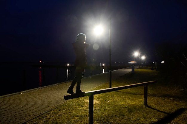 Foto uomo in piedi su una lampada di strada illuminata contro un cielo limpido di notte