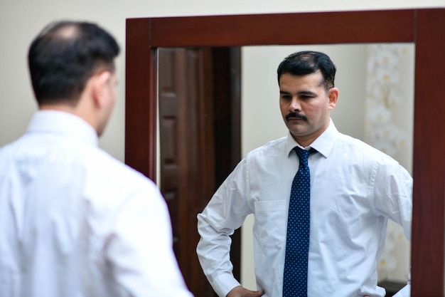 man standing infront of mirror wear white shirt and tie indian pakistani model