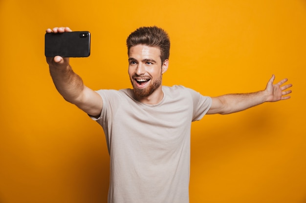 L'uomo in piedi isolato fa un selfie tramite smartphone che mostra copyspace.