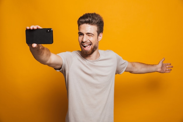 Man standing isolated make a selfie by smartphone showing copyspace.