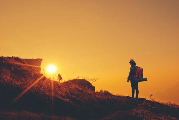 夕暮れの空に照らされた地面に立っている男