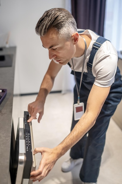 Man standing leaning towards dishwasher looking at control panel