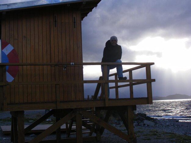 Foto uomo in piedi sulla capanna del bagnino sulla spiaggia