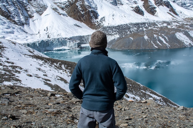 Man standing to look at view of lake with snow mountains