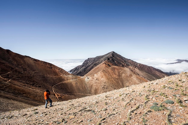 明るい空を背景に山の上に立っている男