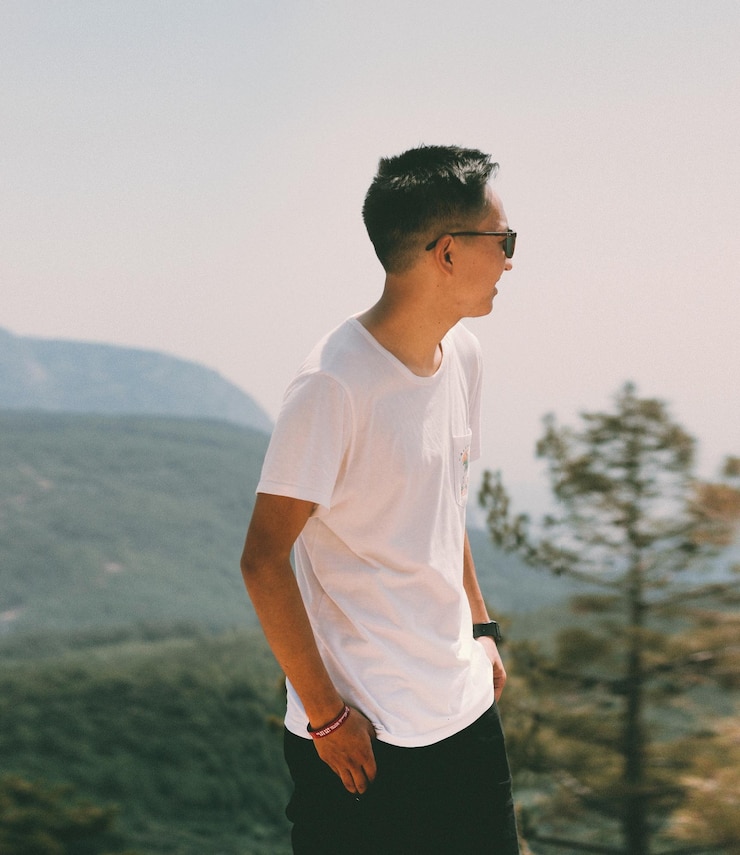 Photo 晴れた日に空に向かって山の上に立っている男