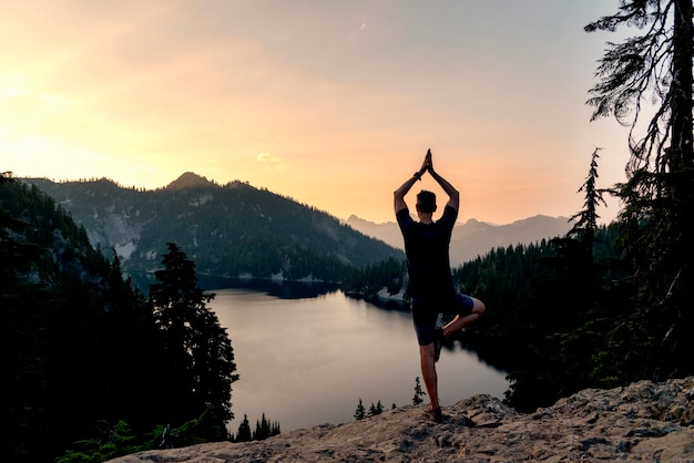 Photo man standing on mountain peak during sunset