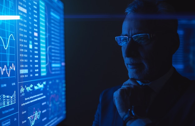 The man standing near the blue screen with chart in the dark room