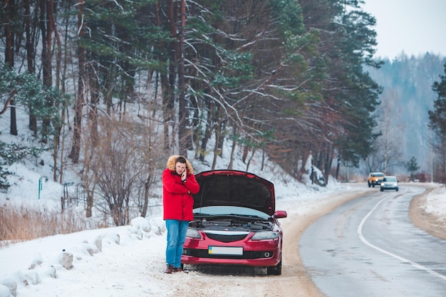 Man standing near broken car with opened hood calling help