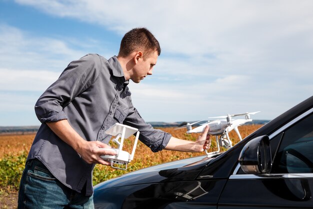 A man standing near the car launches a drone