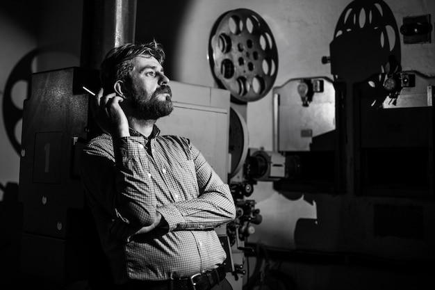 Photo man standing near a film projector in the room projectionist