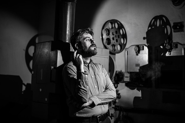 Photo man standing near a film projector in the room projectionist