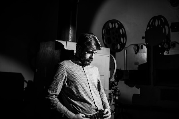 man standing near a film projector in the room projectionist