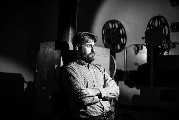 Photo man standing near a film projector in the room projectionist