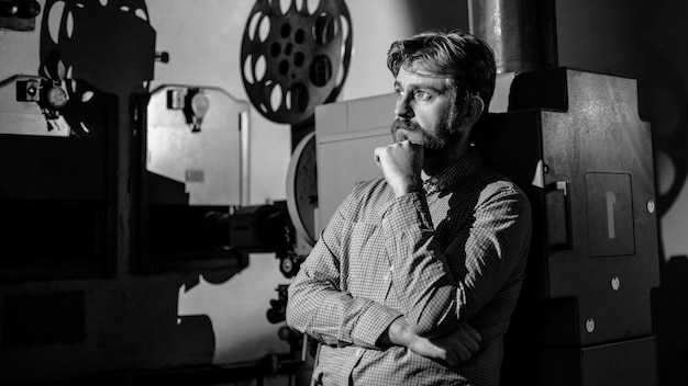 Man standing near a film projector in the room projectionist