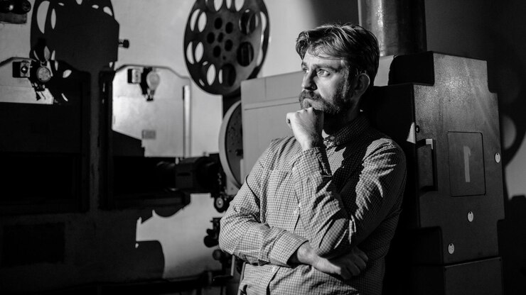 Photo man standing near a film projector in the room projectionist